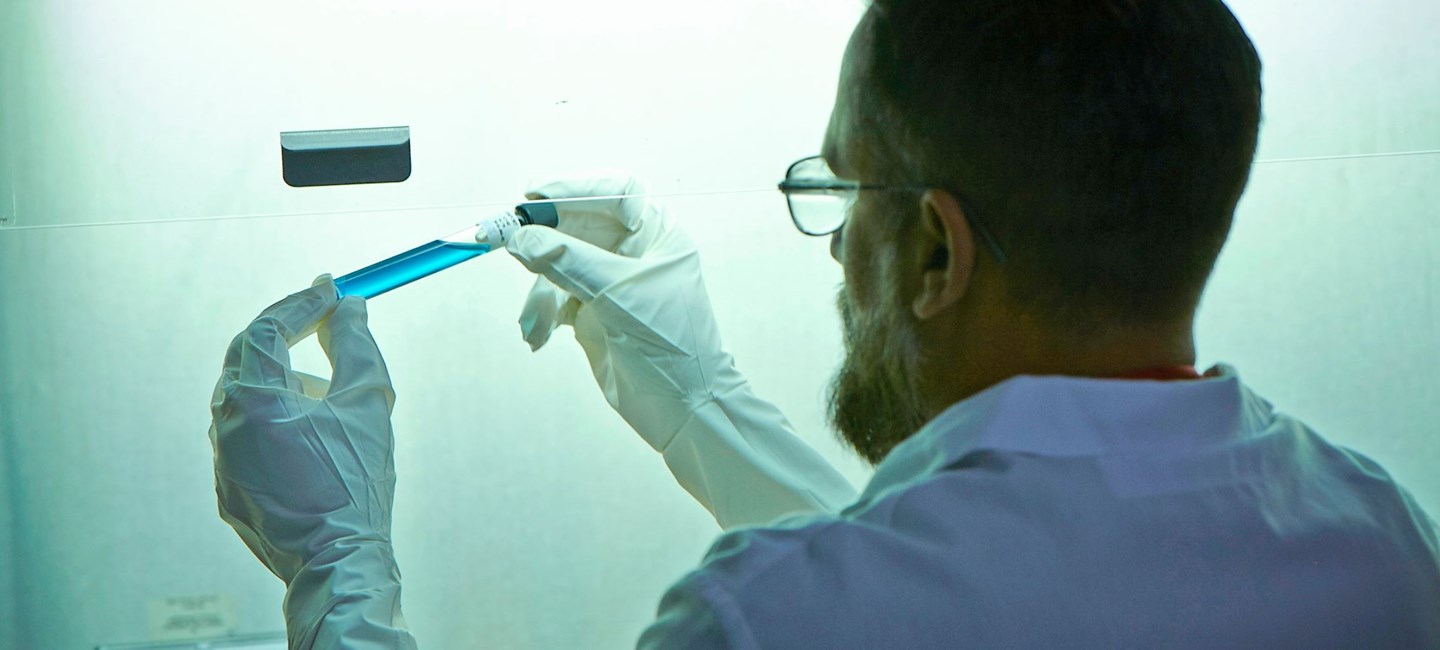 A lab technician holding a vial